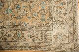 Distressed corner of an Oushak rug, showing aqua blue florals and meandering vine border.