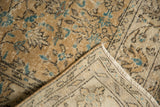 Worn beige distressed Oushak carpet pile, aqua floral motifs, visible foundation and fringe.