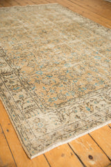 Distressed vintage Oushak rug corner, showing beige, aqua blue floral field, and dark brown border.