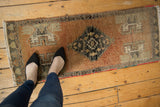 Distressed Oushak runner with a stepped medallion in terra cotta, silver, charcoal, and red selvage.