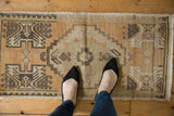 Distressed Oushak runner, faded geometric patterns in beige, brown, and seafoam.