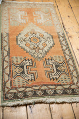 Distressed Oushak rug corner with orange rust, beige, geometric border, and worn fringe.
