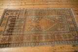 Distressed Oushak rug with muted copper, brown, and grey geometric starburst patterns.