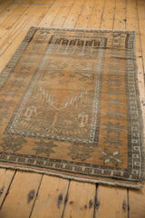 Distressed vintage Turkish Oushak rug corner, copper terra cotta starbursts, and fringed edge.
