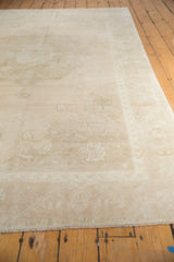 Distressed Oushak carpet's even low pile texture, muted beige patterns, and short fringe.