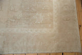 Distressed vintage Oushak corner detail with low pile, subtle patterns, and secured edge.
