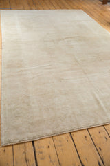 Side edge of a distressed vintage Oushak carpet showing soft low pile and ivory beige patterns.