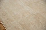Distressed hand-knotted Oushak carpet with even low pile, faint medallion, and muted ivory beige tones.