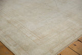 Corner of vintage distressed Oushak rug with intricate ivory and silver geometric border.