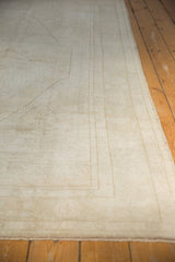Distressed Oushak carpet's low pile texture and secured side in ivory tones.