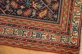 Antique Serbend rug corner with navy field, splayed floral motifs, and terra cotta geometric borders.