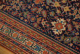 Vibrant terra cotta border and navy field with splayed floral motifs on an antique Serbend rug.