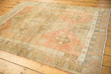 Distressed vintage Oushak rug detail: soft wool pile, geometric diamond motifs, blush and bronze tones.