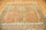 Distressed geometric floral diamond design elements in blush and pale bronze on a vintage Oushak rug.