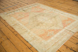 Distressed edge of a vintage Oushak rug with abrashed blush, ivory, and pale bronze tones.