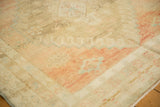 Distressed Oushak rug's soft wool pile, revealing blush, pale bronze, and powder blue geometric patterns.