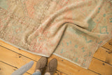 Distressed vintage Oushak rug showing soft, even wear and faded blush and seafoam tones.