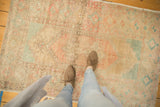 Distressed vintage Oushak rug displaying worn pile in blush, seafoam, and sand tones.