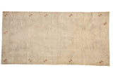Vintage distressed Oushak carpet in ivory with a faint medallion and sparse copper pinwheel border details.
