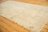 Tone-on-tone antique ivory field showing low pile texture and small copper pinwheel accents.