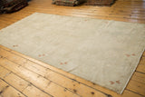 A distressed Turkish Oushak rug's spacious ivory field and copper motifs viewed from a high angle.
