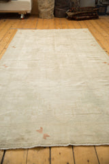 Low angle view of a vintage Oushak rug's subtle, tone-on-tone pattern and distressed texture.