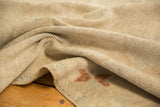 A close-up view of the distressed, low pile texture of a vintage Oushak carpet.