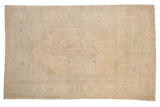 Distressed vintage Oushak carpet with a faint medallion and corner spandrels in soft ivory, sand, and pale blue.