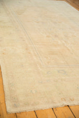 Low angle showing the even, low pile texture of the distressed Oushak carpet in soft sand and ivory tones.