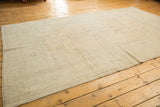 Vintage distressed Oushak carpet viewed lengthwise, showing its pale open field and subtle design.
