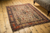 Afshar rug corner detail: redone selvages, ivory ground, and brick red border with wear.