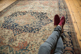 Antique Farahan Sarouk rug's central medallion and floral field, with feet resting.