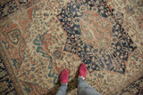 Antique Persian Farahan Sarouk carpet with intricate floral design, visible wear, and feet.