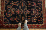 Antique Mohajeran Sarouk rug, navy field of bursting florals, wine red palmette border, with feet.