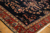 Intricate palmette border and blooming floral navy blue field of an antique Mohajeran Sarouk rug.