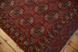 Geometric 'elephant footprint' gul motif in madder red, navy, and ivory with a worn border edge.