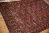 Geometric elephant footprint gul motifs in madder red and dark navy on vintage Turkmen rug, with visible pile wear.
