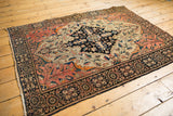 Antique Farahan Sarouk rug corner, classic navy palmette border, blush vinery with even wear.