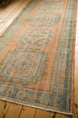 Textured distressed Oushak runner with faded apricot, pale blue, and mint floral guls.