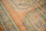 Vintage Oushak rug's distressed pile showing pale apricot, mint, and blue floral guls.