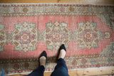 Distressed vintage Oushak runner showcasing soft blush, ivory, and sand tones with even wear.
