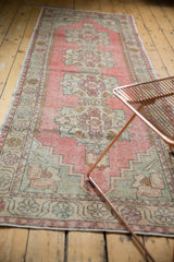 Blush pink, ivory, green distressed Oushak runner's Rococo medallion and vine border.