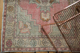 Distressed Oushak runner with worn blush, soft green, ivory palette and floral motifs.