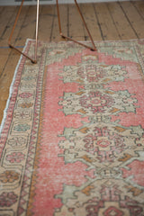 Distressed pile of a vintage Oushak runner in blush, ivory, and sand tones.