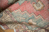 Distressed Oushak rug with even pile wear and blush, sage, sand patterns.