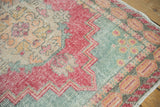 Distressed Oushak runner with faded red, slate blue, and gold Rococo floral motifs.