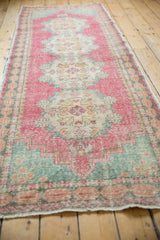Distressed Oushak rug edge showcasing faded red and slate blue gray panel border, with faint foundation showing.