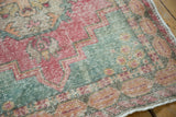 Faded pink and slate blue gray Rococo motifs on a distressed vintage Oushak rug.