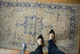 Distressed vintage Turkish Oushak runner, featuring faded navy blue medallion and scrolling border.