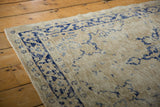 Distressed Oushak rug with navy cobalt blue scrolling vine border and wear with etching.